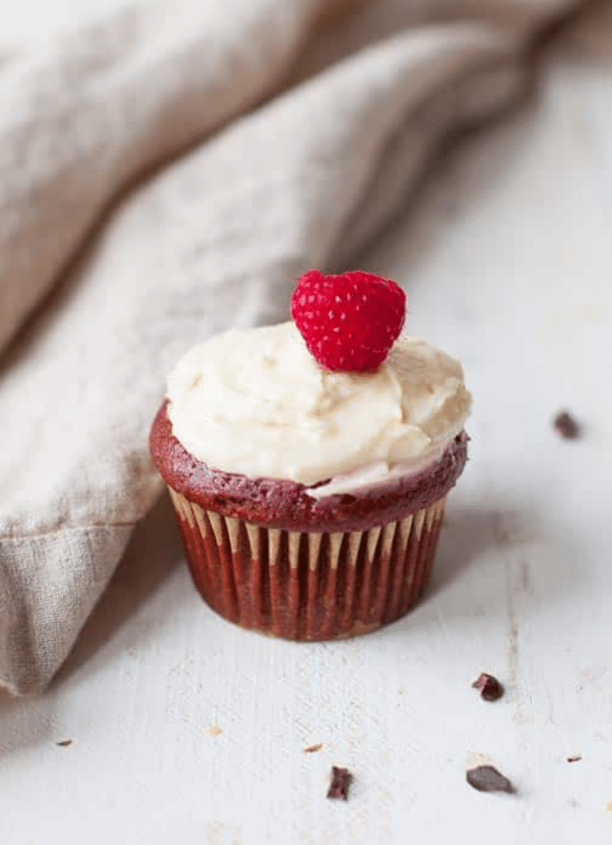 red velvet cupcake with frosting and a raspberry on top