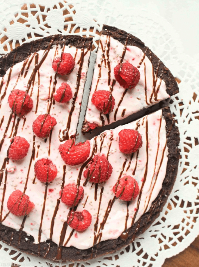 chocolate brownie pizza with frosting and raspberries on top