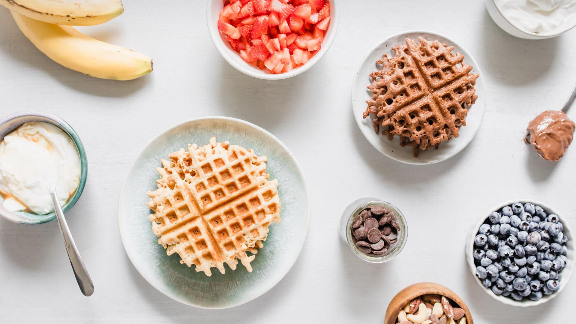 Waffles and waffle toppings in individual dishes on a table