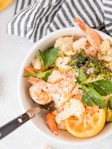 square image of shrimp and vegetables in a bowl with a fork in it