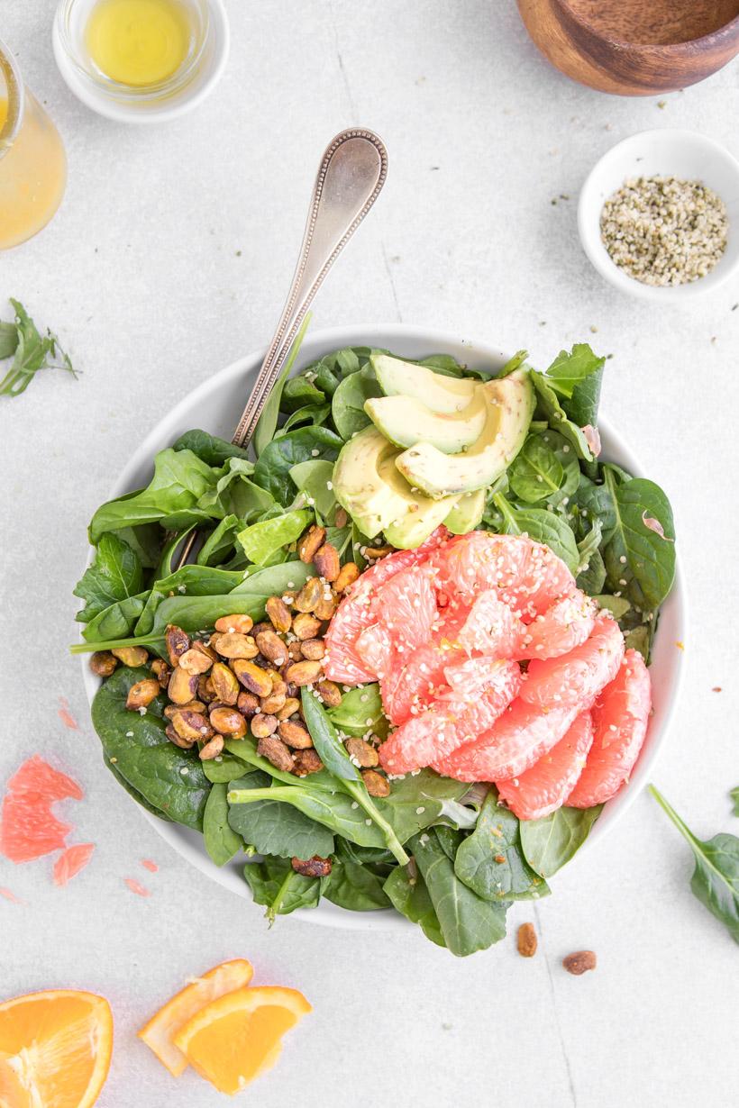 avocado grapefruit and spinach in a bowl with a fork in it