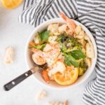 shrimp sheet pan dinner in a bowl with bread on the side