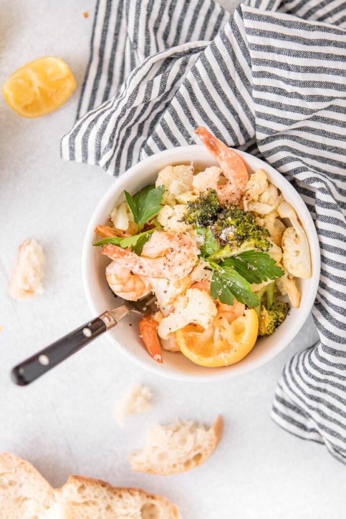 shrimp sheet pan dinner in a bowl with bread on the side