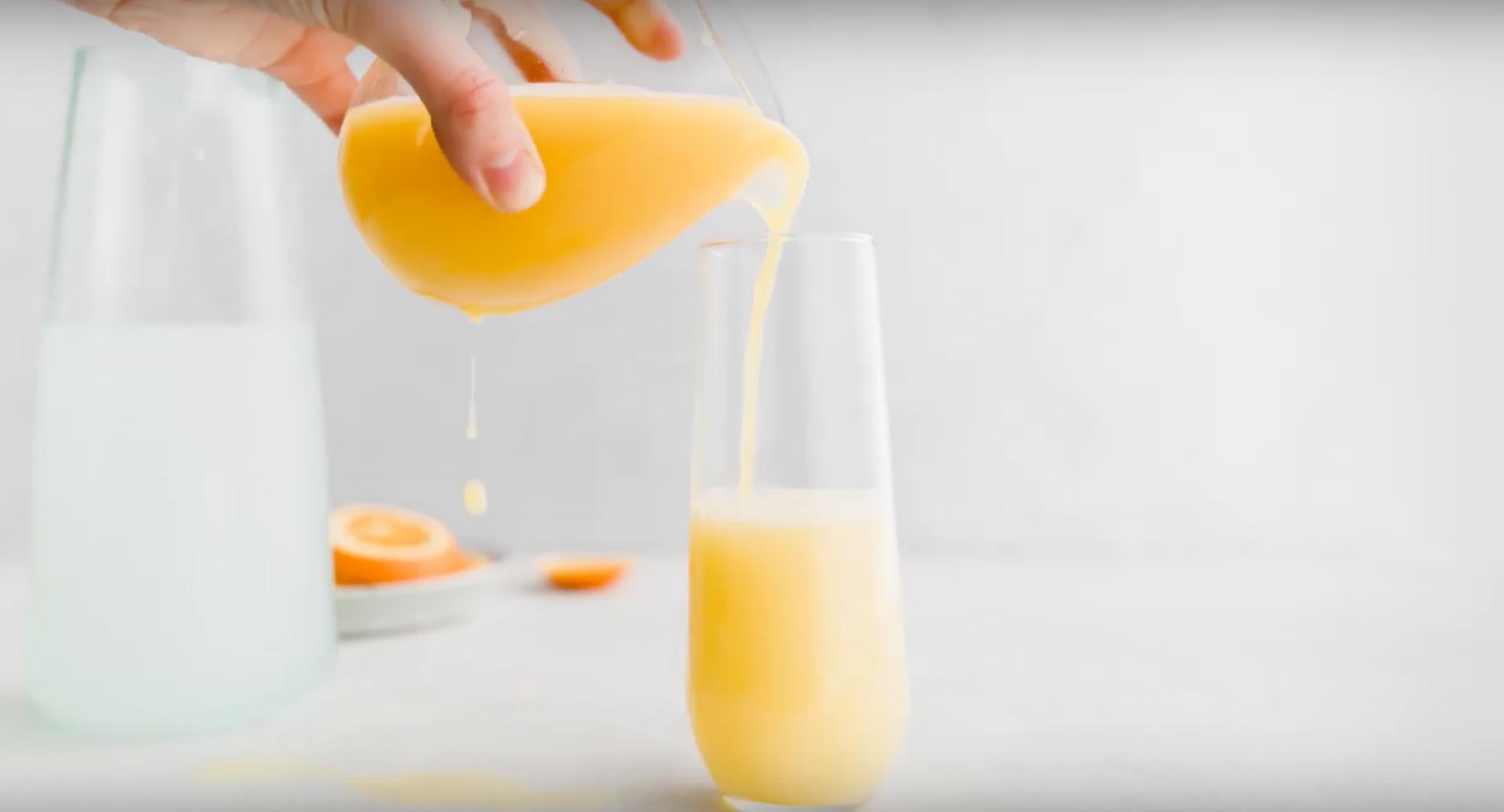 pouring orange juice into champagne glass