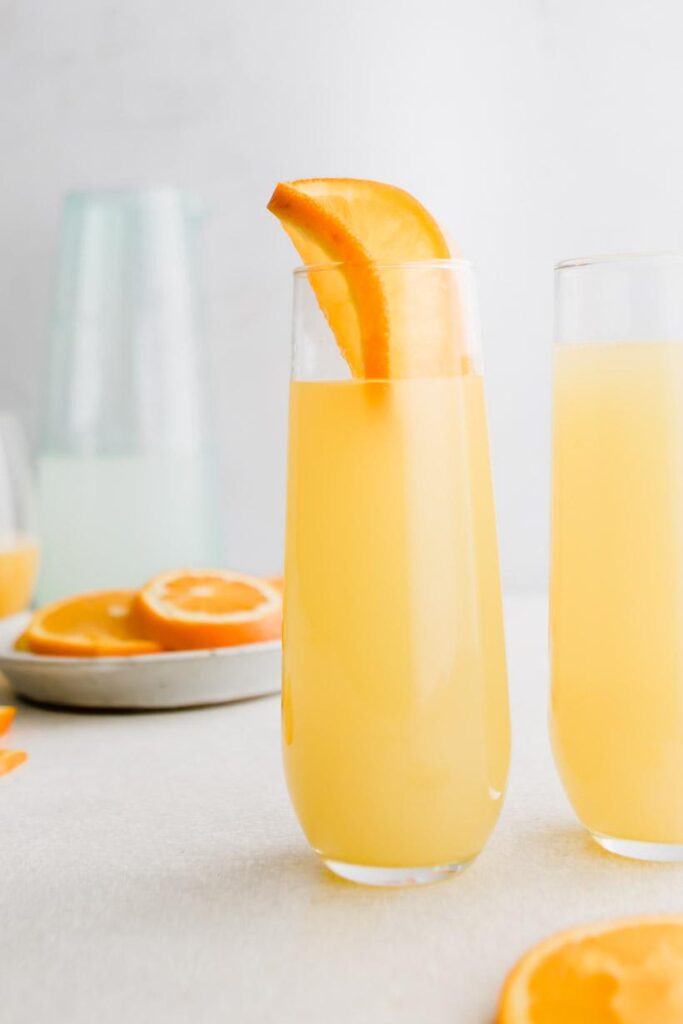 mimosa mocktail in a glass with oranges in background