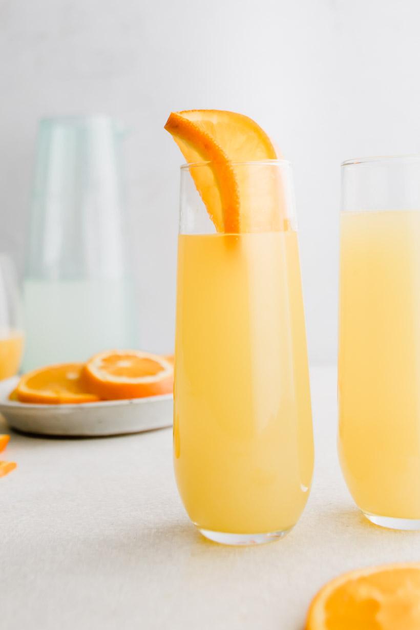 mimosa mocktail in a glass with oranges in background