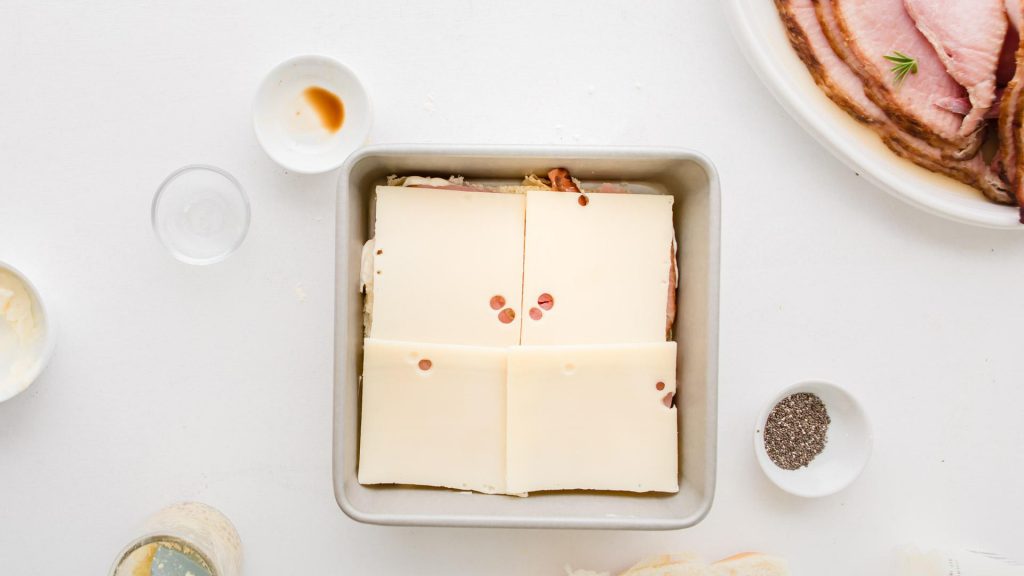 ham and swiss cheese on rolls in a square baking dish