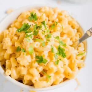 close up of mac and cheese in a bowl with parsley on top