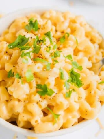 close up of mac and cheese in a bowl with parsley on top