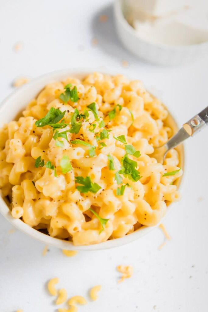 close up of mac and cheese in a bowl with parsley garnish