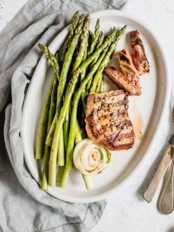 lamb steak and asparagus on a white oval plate