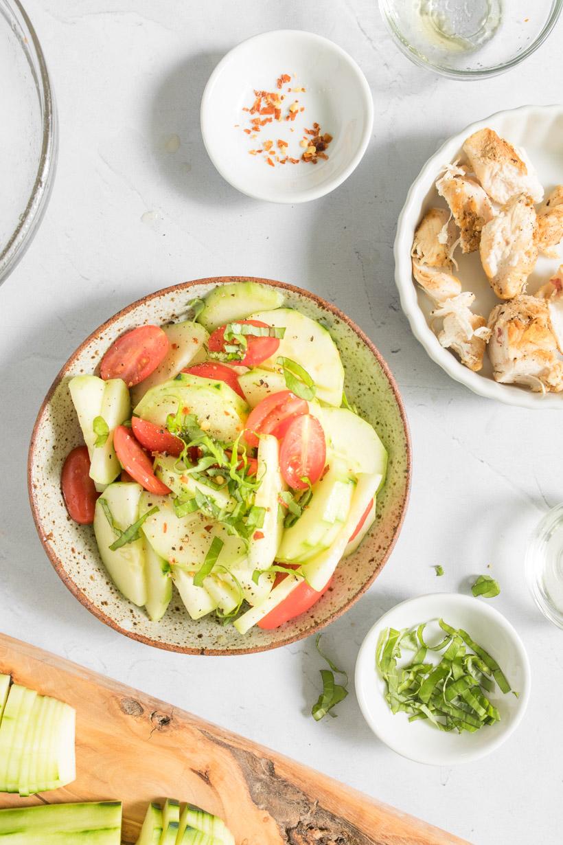 cucumber and tomatoes with basil on top salad in a bowl