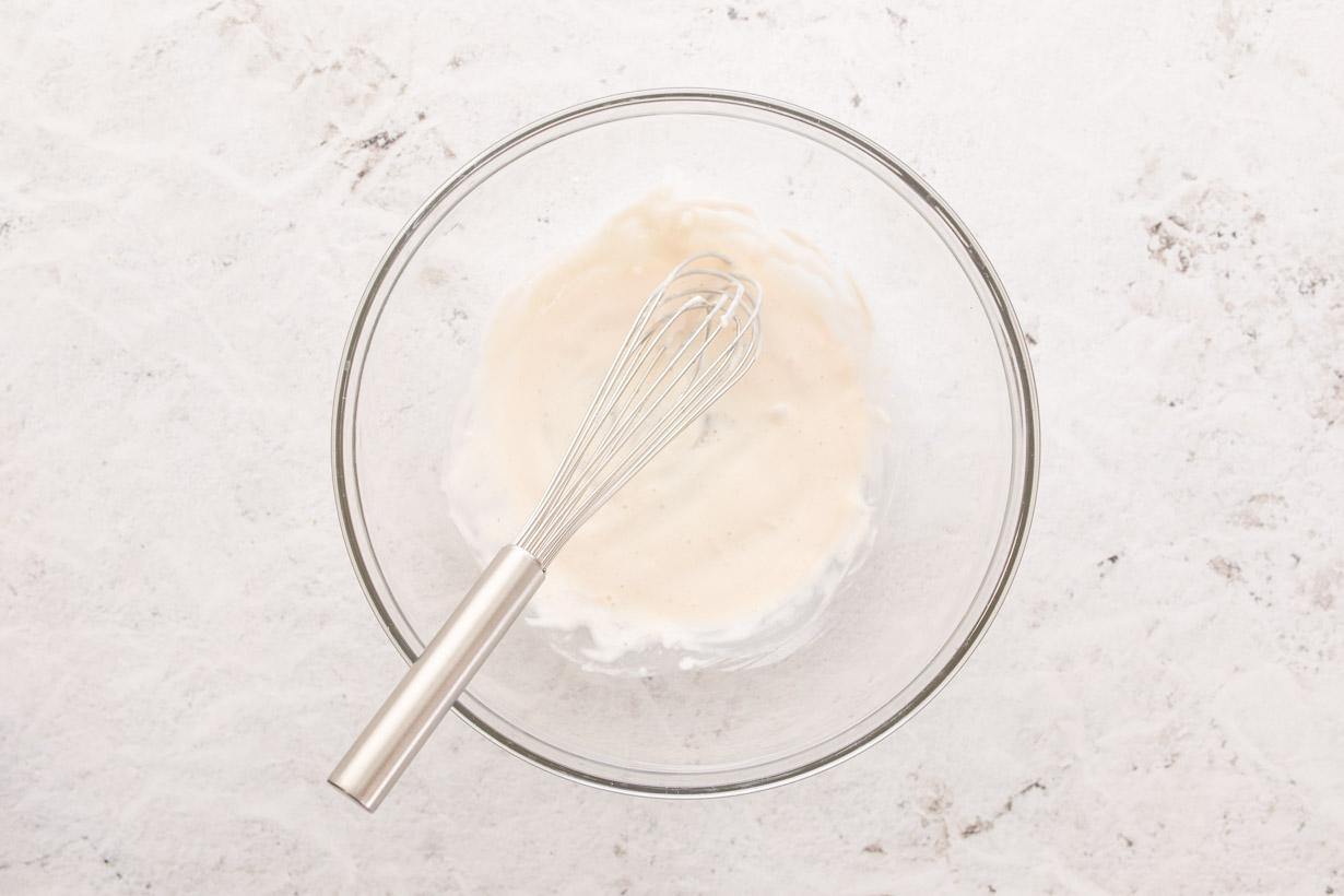 white salad dressing in a glass bowl with whisk
