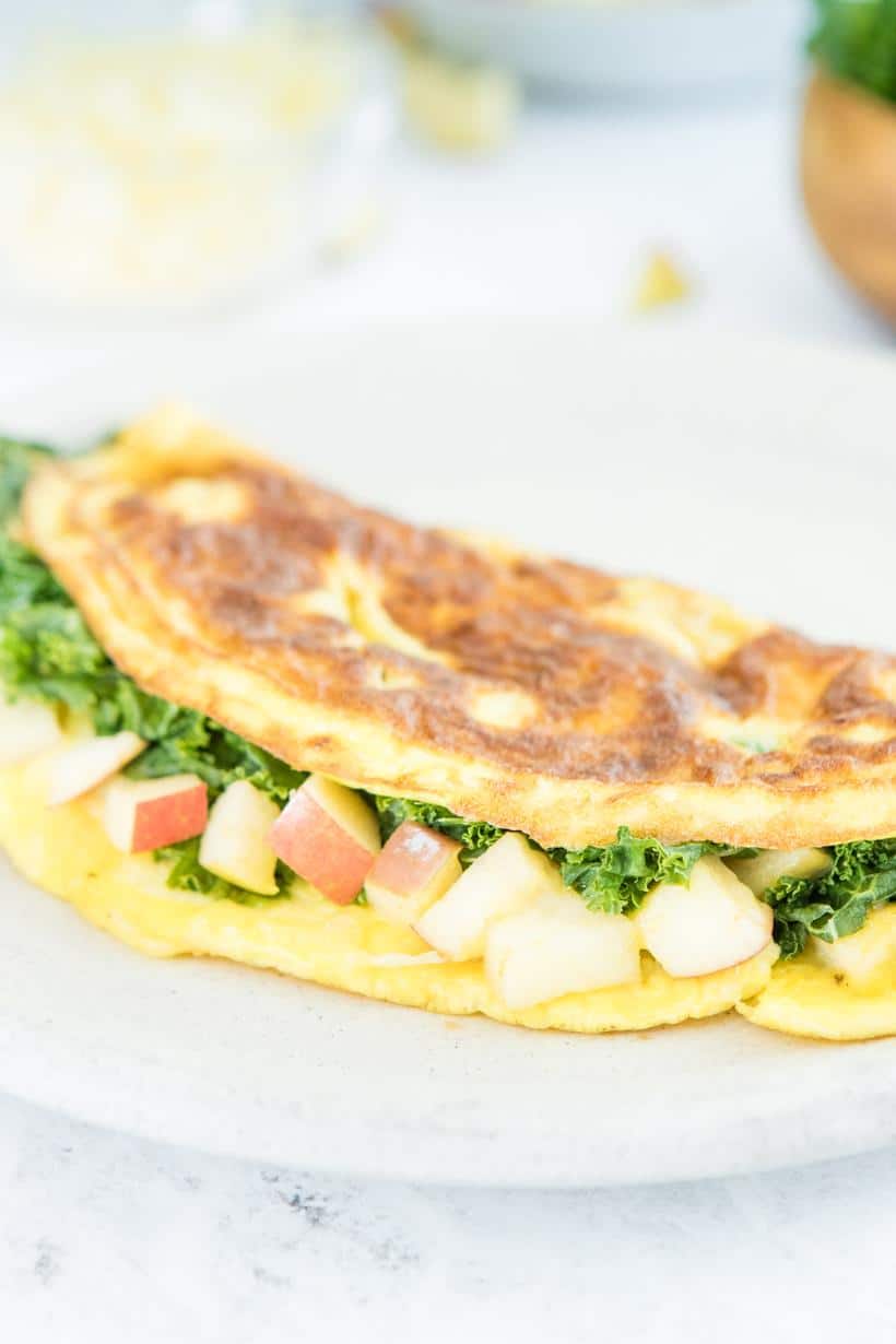 close up of an omelette with kale and apples on a plate