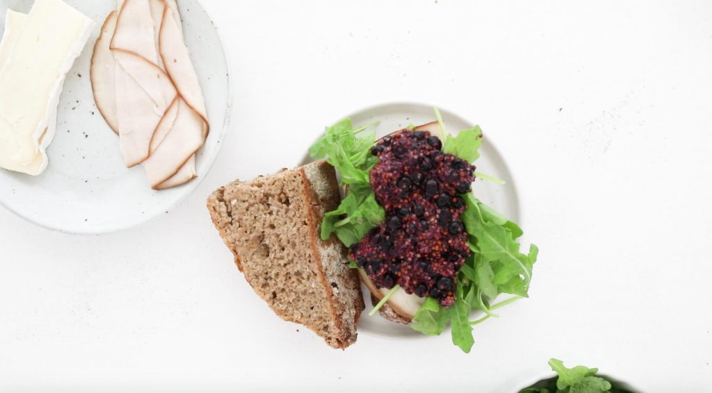 open faced turkey sandwich with arugula and blueberry mustard with other slice next to it