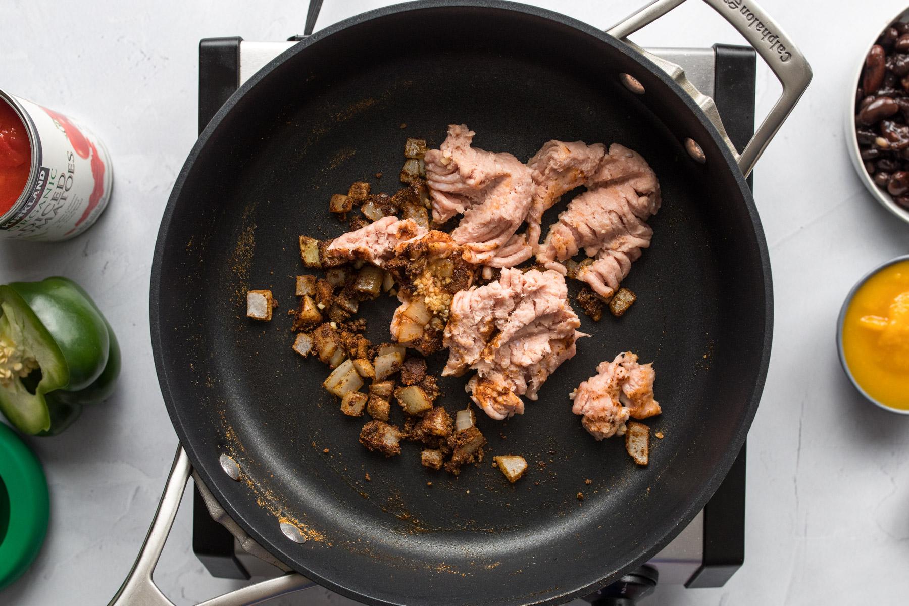 onions and spices in a small skillet, with a spatula in it