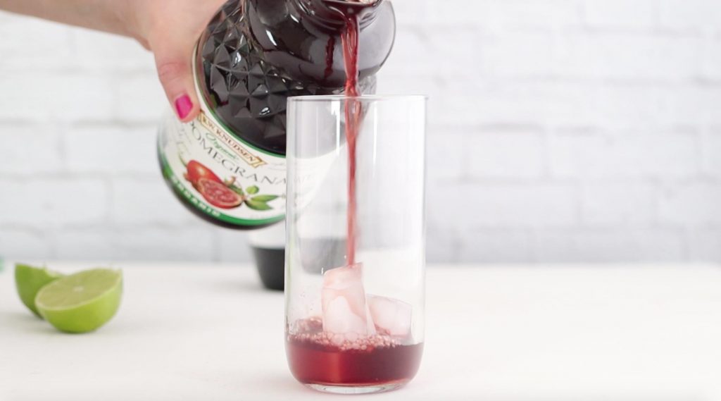 pouring pomegranate juice into a tall glass