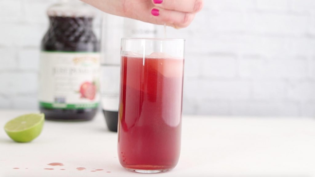 squeezing lime juice into pomegranate spritzer