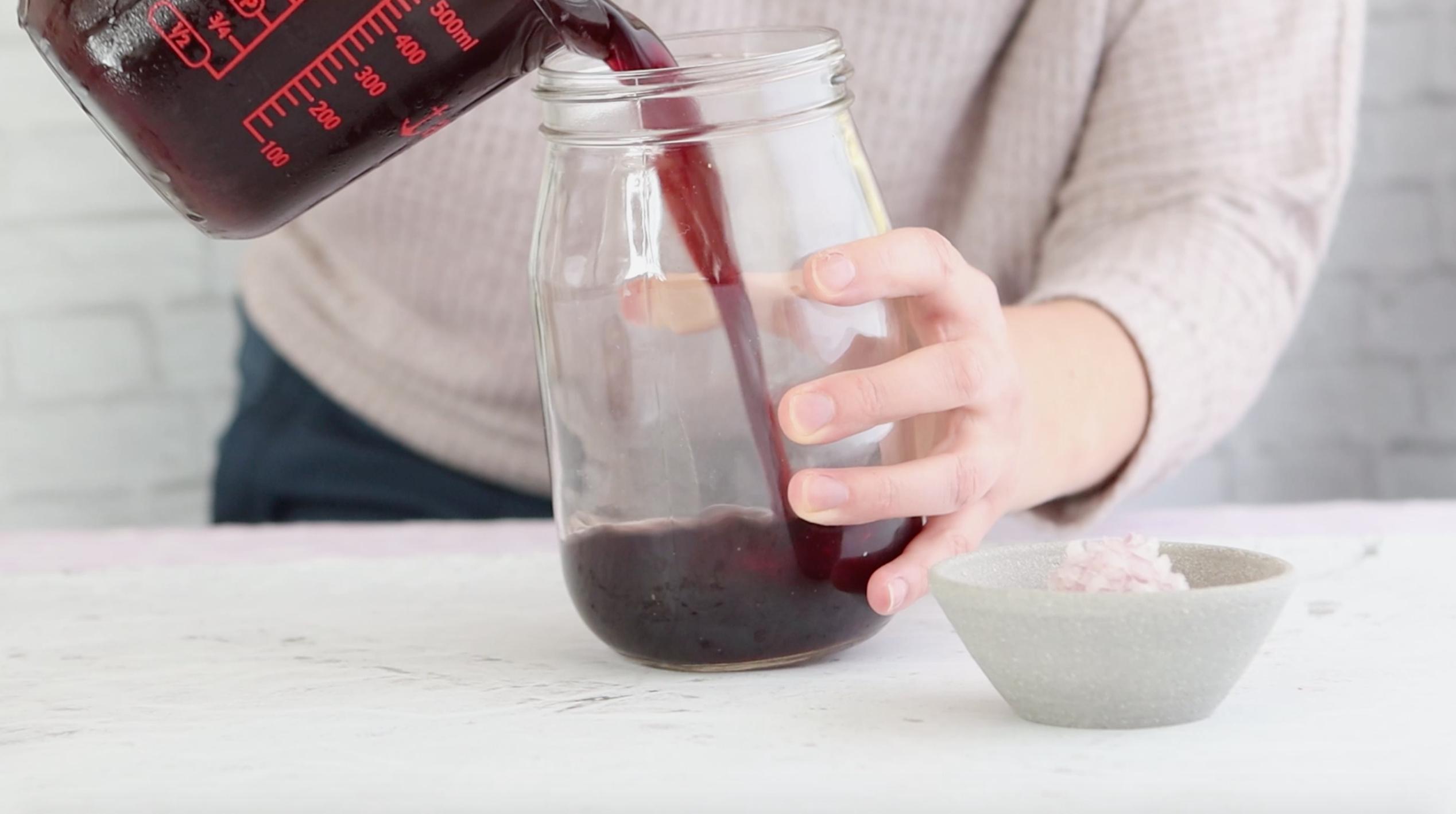 pouring pomegranate juice into a mason jar