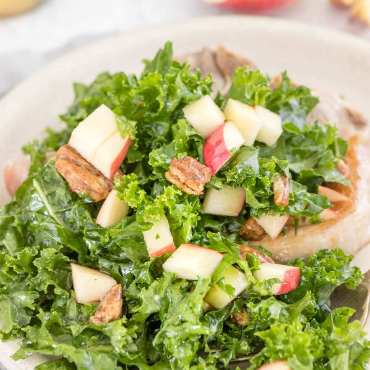 kale salad with pecans and apples on a pork chop