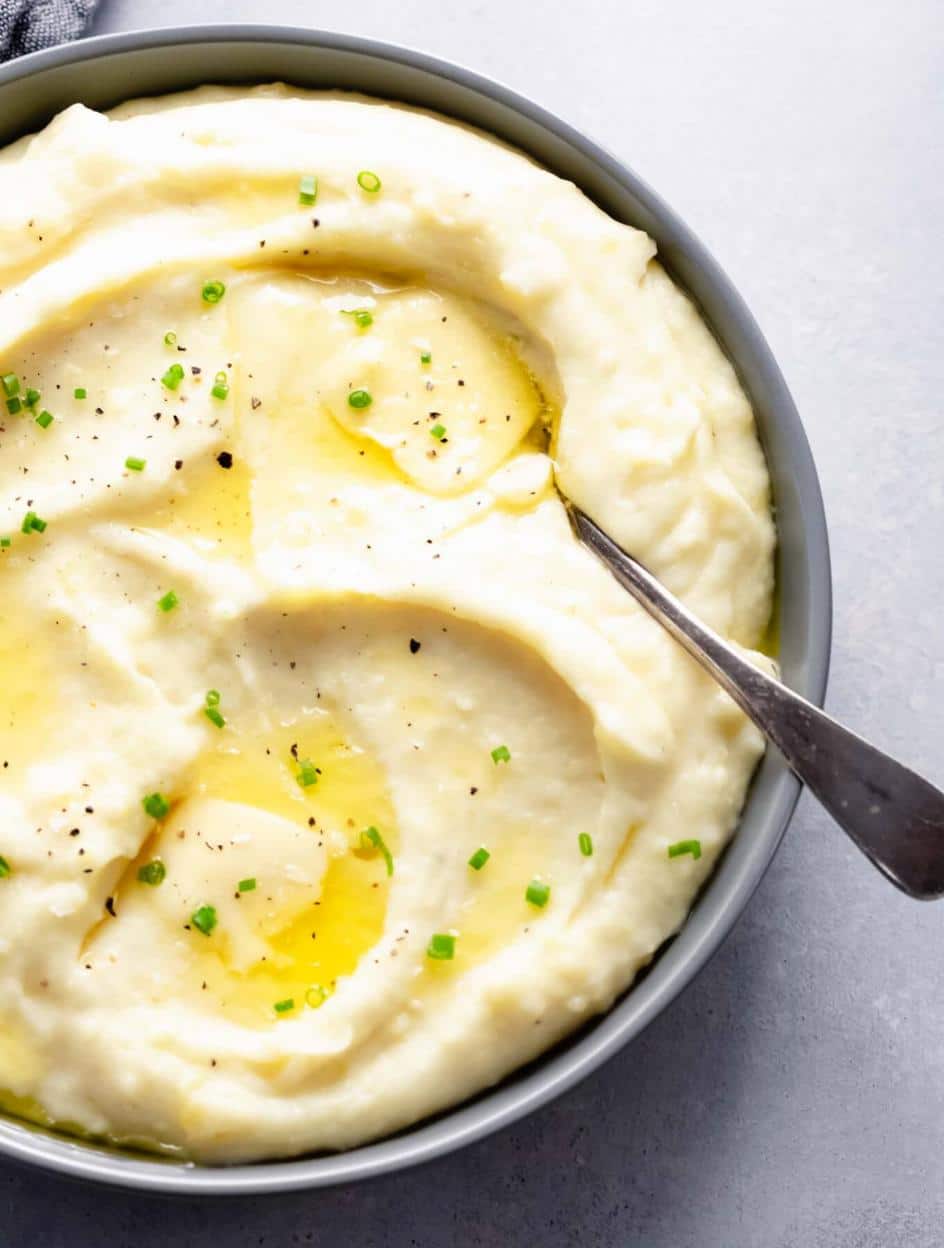 close up shot of mashed potatoes with butter and chives on top