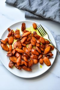 roasted carrots on a white plate with a blue towel next to it