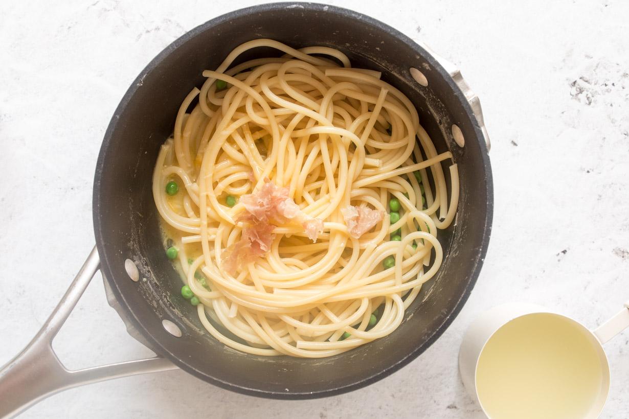 pasta, prosciutto, and peas in a black pot