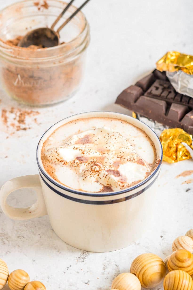 3 ingredient hot cocoa in a mug with ingredients surrounding it