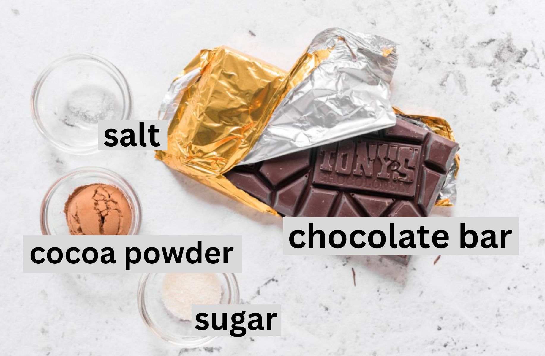 chocolate bar, sugar, cocoa powder, and salt on a table