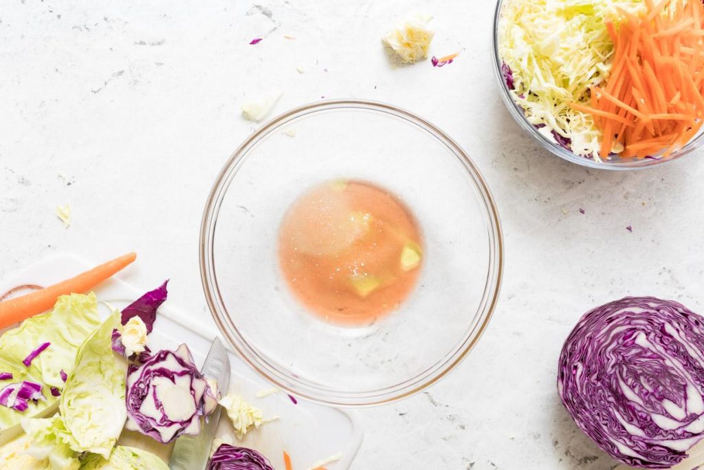 red wine vinegar dressing in a glass bowl next to shredded veggies