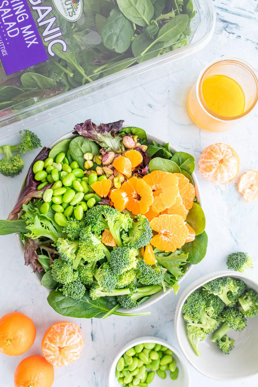 spinach salad with mandarin oranges in a large bowl with ingredients around it