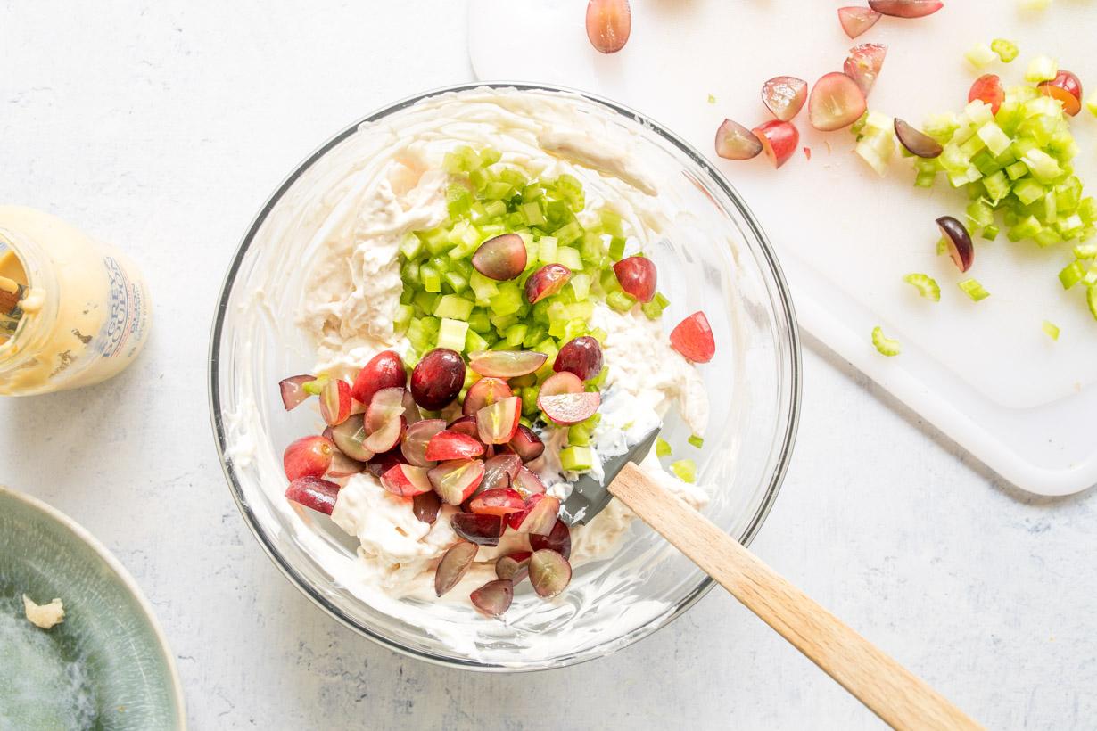 chicken salad in a glass bowl with red grapes and celery on top