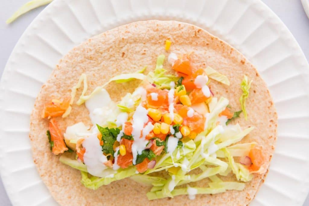 fish tacos with white sauce and citrus salsa on a tortilla