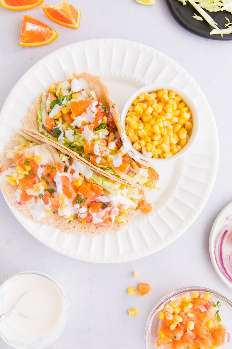 fish tacos with white sauce and orange salsa on a white plate