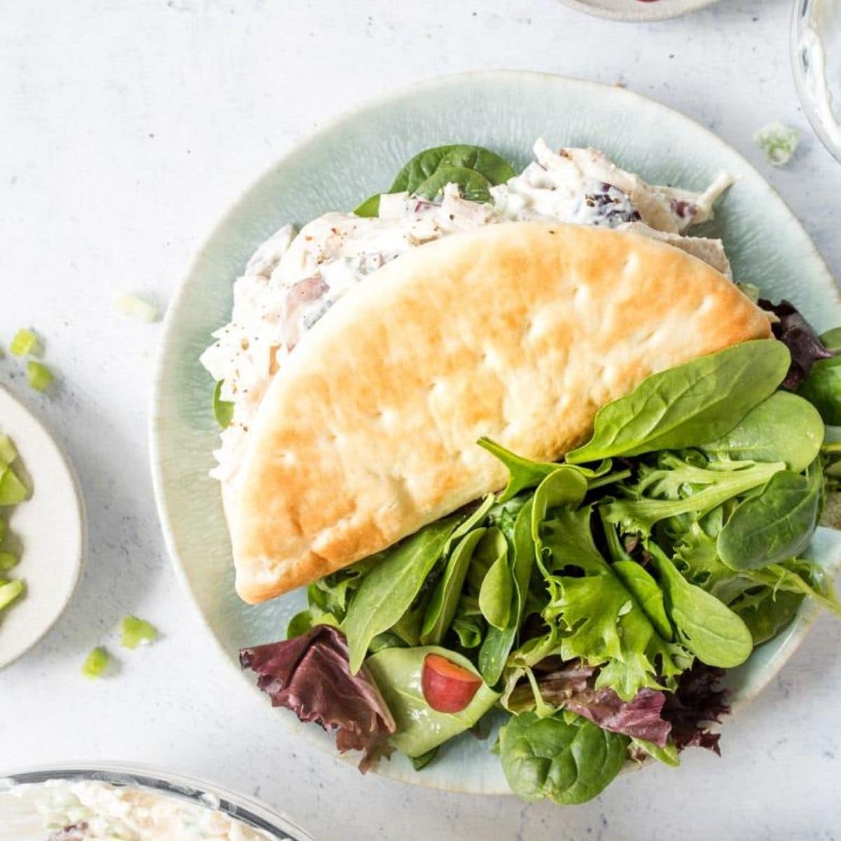 pita filled with chicken salad and salad on plate