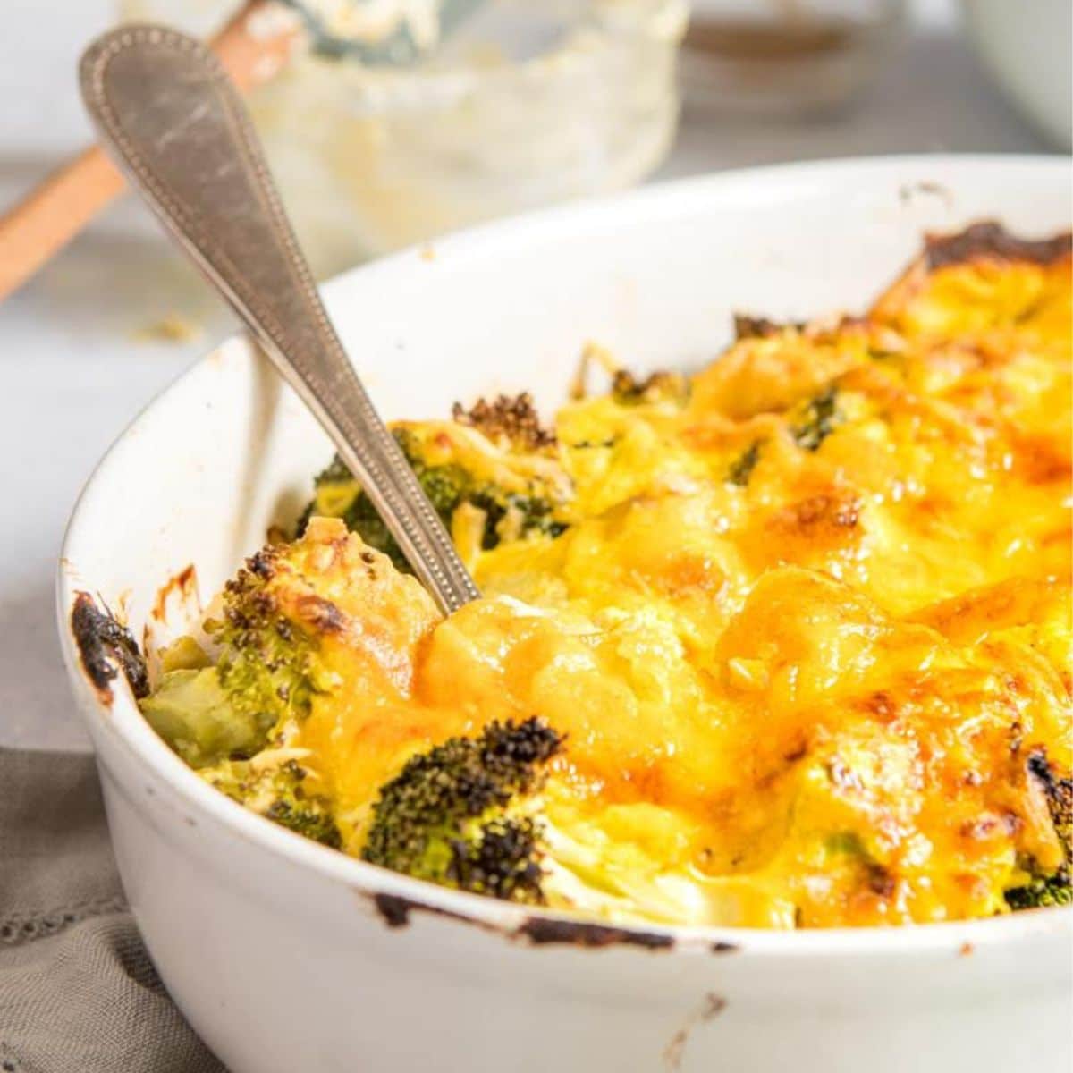 close up of cheesy broccoli in white casserole dish