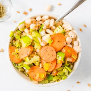 close up of carrots, leeks, and white beans in a bowl