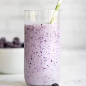 blueberry smoothie in glass, with straw