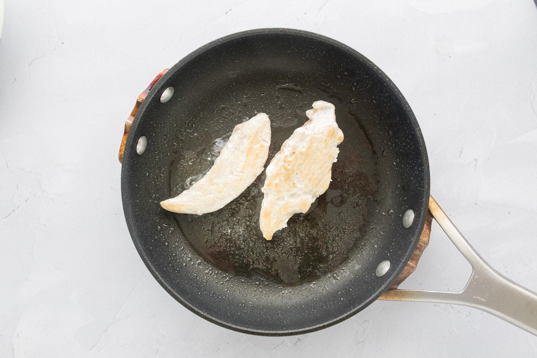 two chicken tenders in a small frying pan