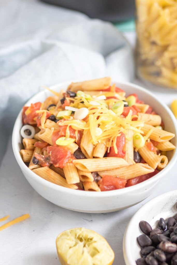 black bean pasta in a white bowl with ingredients around it