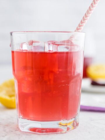 passion tea in a glass with ice and a pink straw