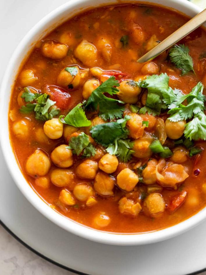 chana masala with cilantro on top in a white bowl