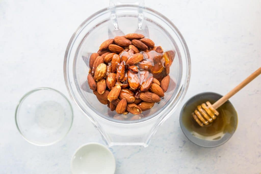 ingredients for honey almond butter in a blender jar