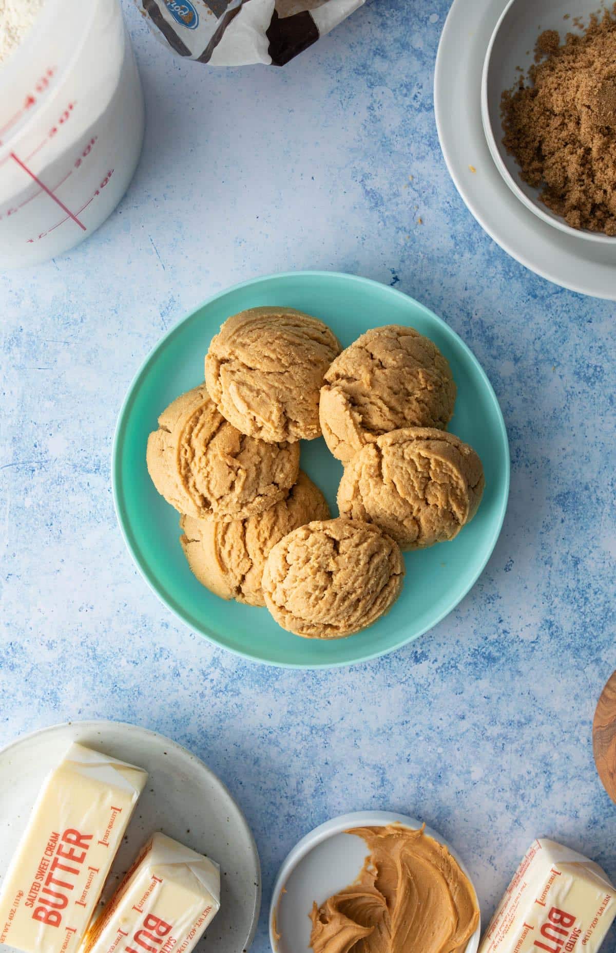 Hand grabbing one of 5 peanut butter cookies on a cooling rack