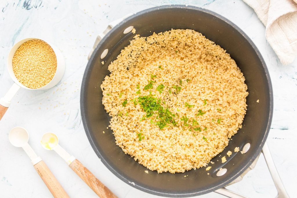 cooked couscous with herbs in a black pot