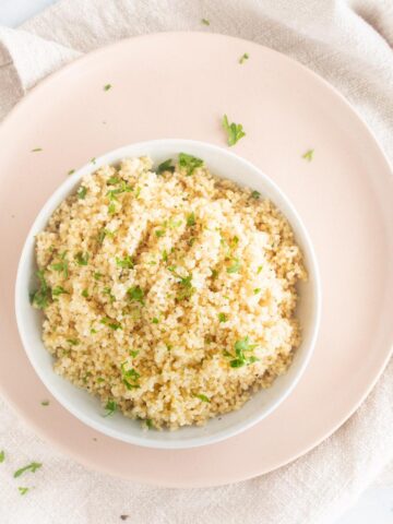 couscous in a white bowl with parsley on top