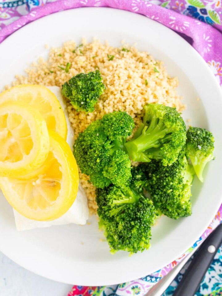 cod with lemon on top next to couscous and broccoli