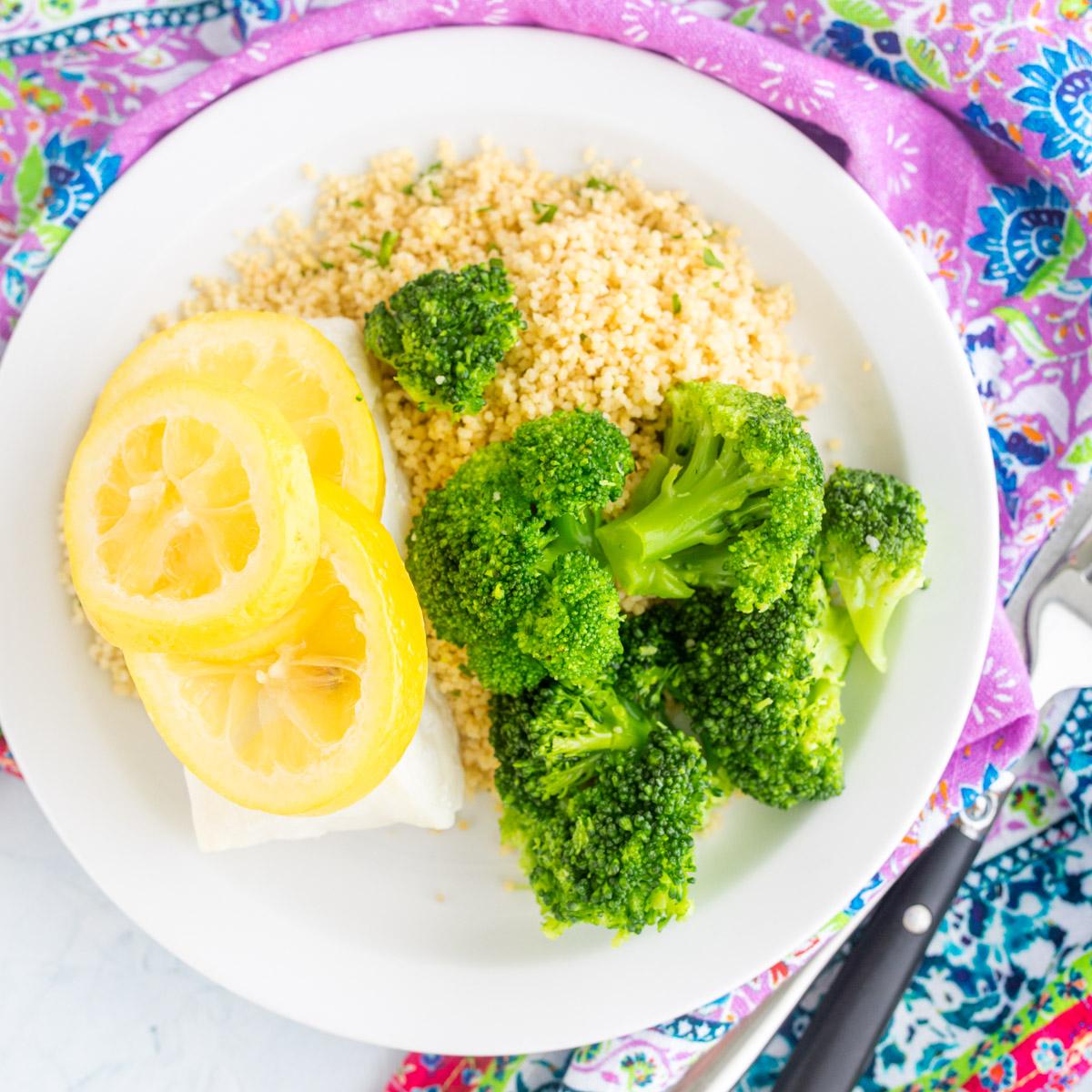 cod with lemon on top next to couscous and broccoli