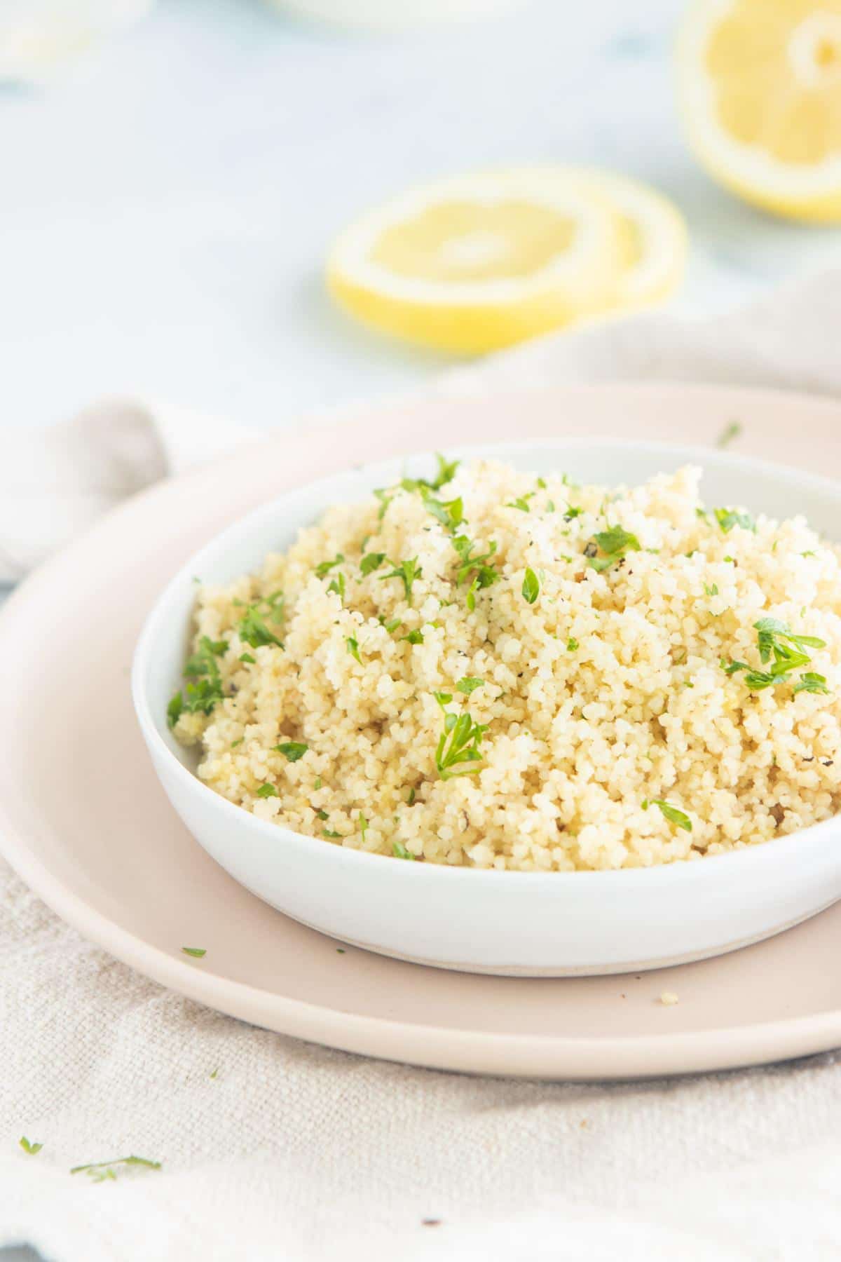 couscous on a pink plate with lemons in back