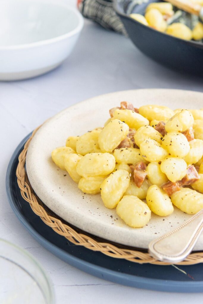 gnocchi carbonara with salami on a plate with gnocchi in the background